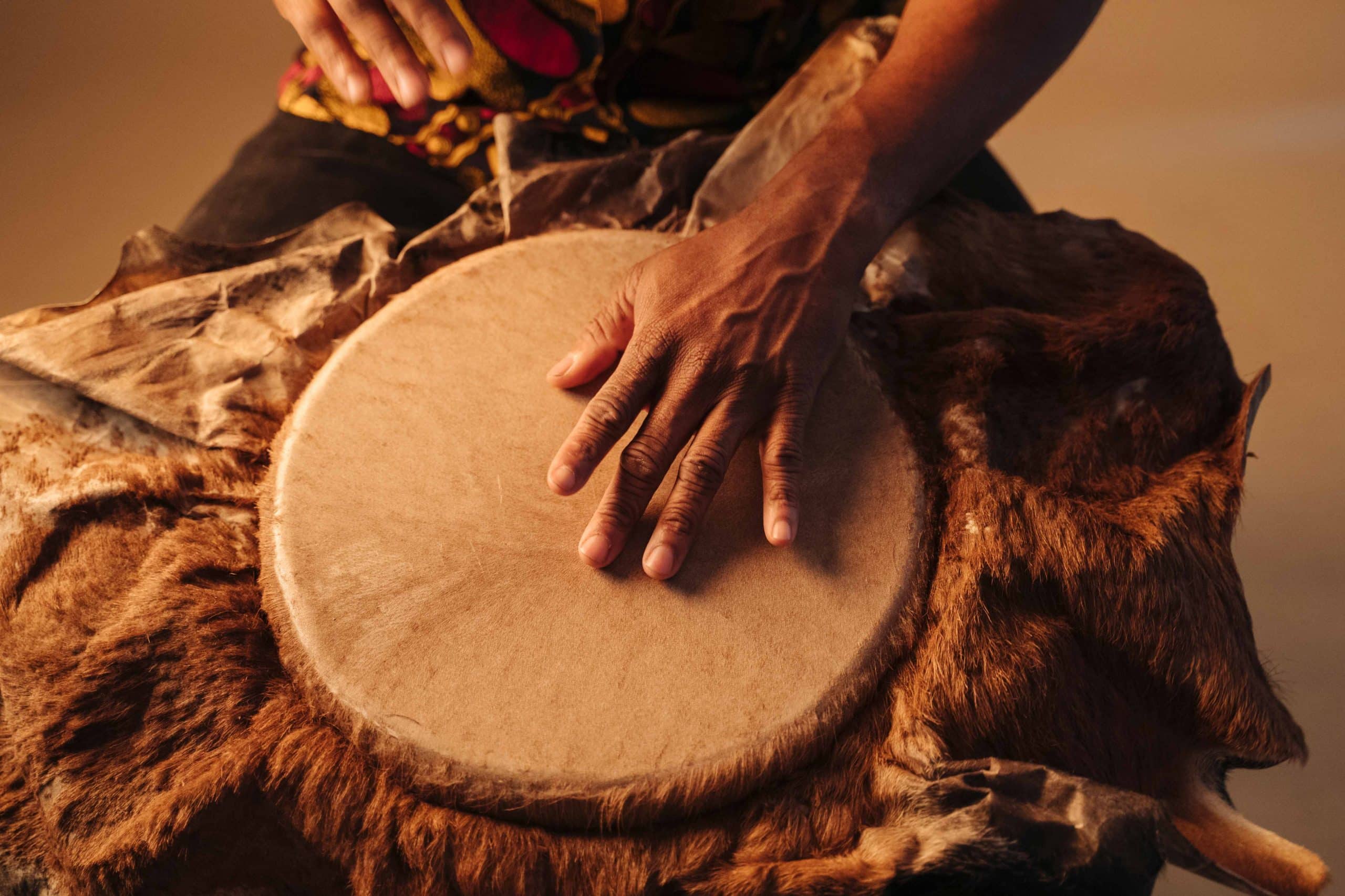 Detail of african american man musician playing traditional drums at brown background.