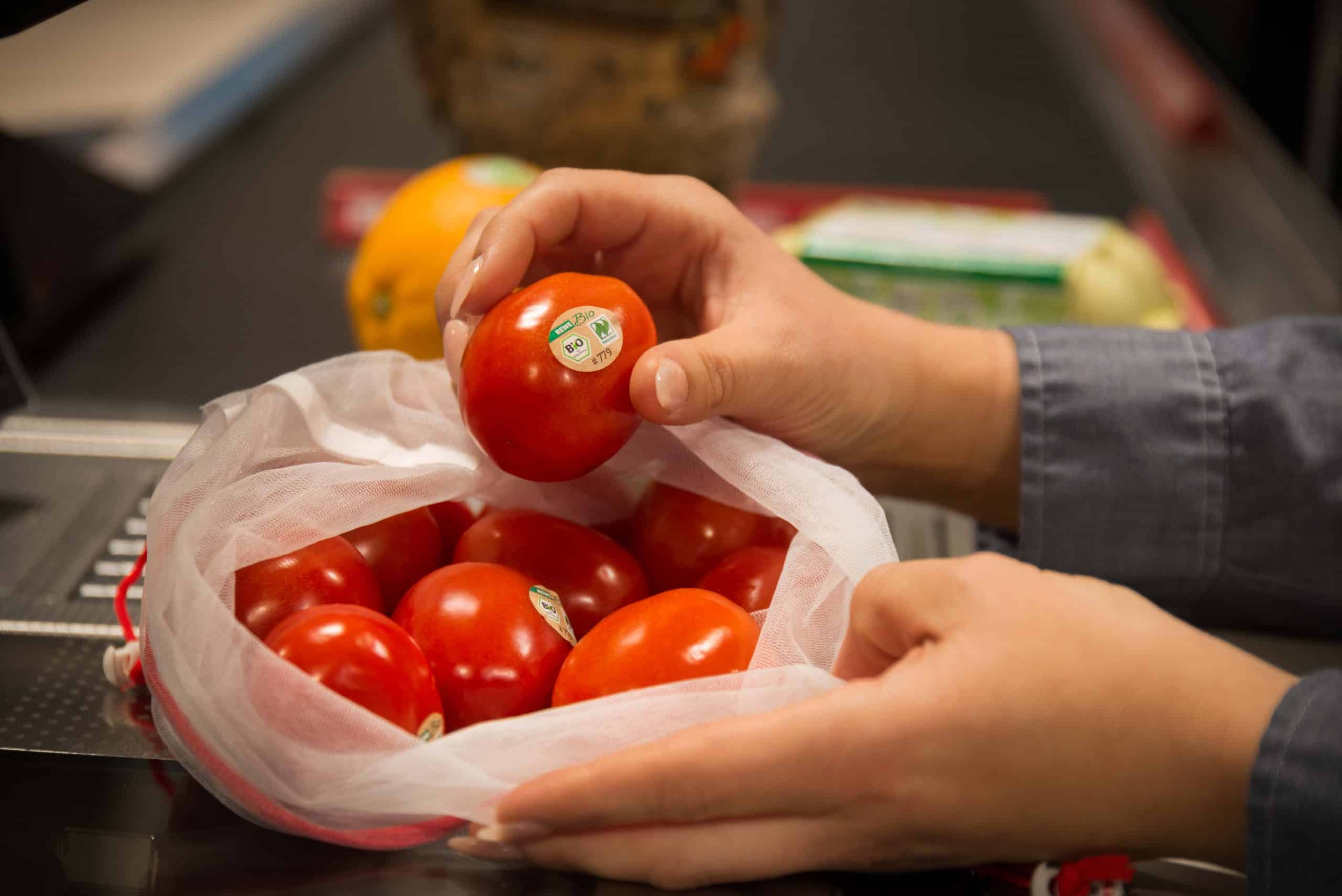 Bio-Tomaten in einem Netz auf dem Kassenband