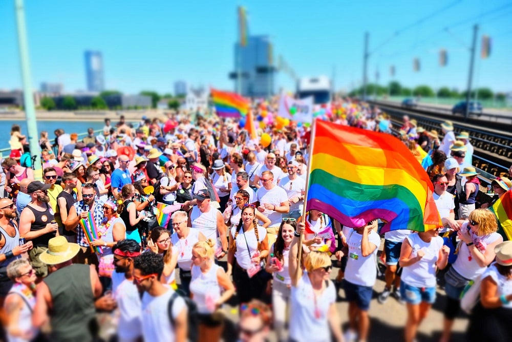Eine Gruppe von Mitarbeitenden mit LGBT-Flaggen auf der Pride Parade als Symbilbild für Diversity bei der REWE Group