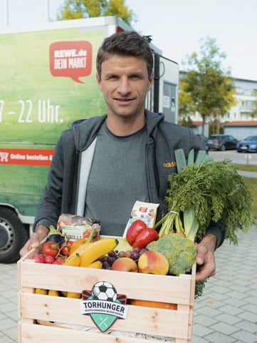 Thomas Müller mit einem Korb mit Obst und Gemüse für Torhunger