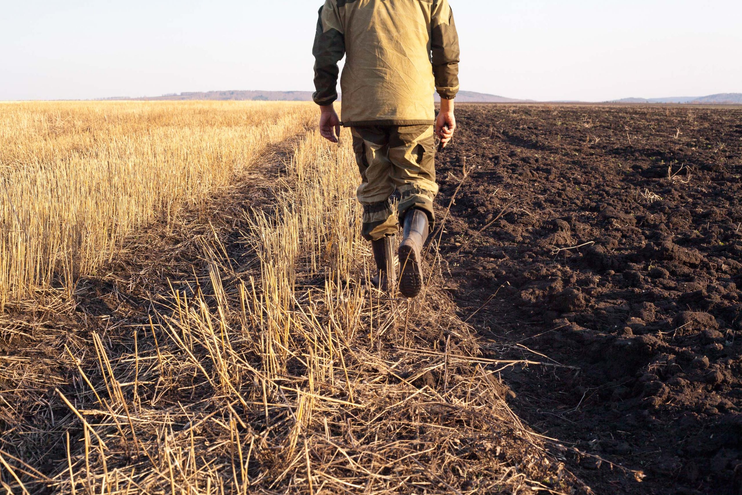 Ein Bauer geht über sein Feld. Ein Symbolbild für unsere Zusammenarbeit mit Landwirt:innen in der Landwirtschaft