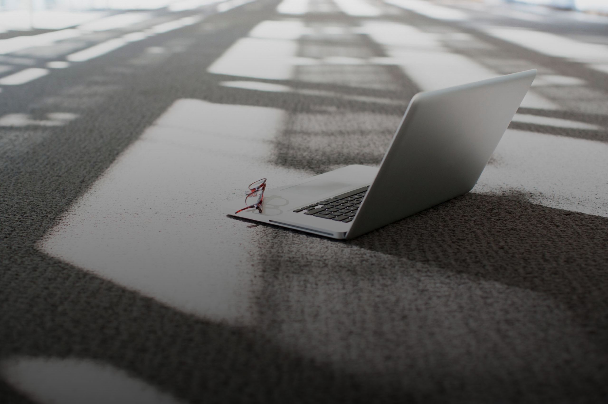 Ein Laptop steht auf dem Boden. Eine Brille liegt auf der Tastatur. Ein Symbolbild für unserem Creditor Relations Bereich