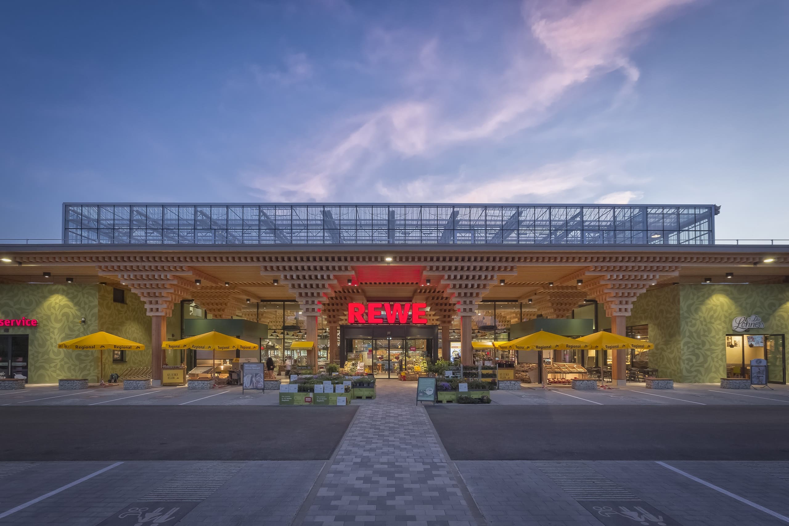 Außenansicht bei Nacht des neuen REWE Green Building Markts in Wiesbaden.
