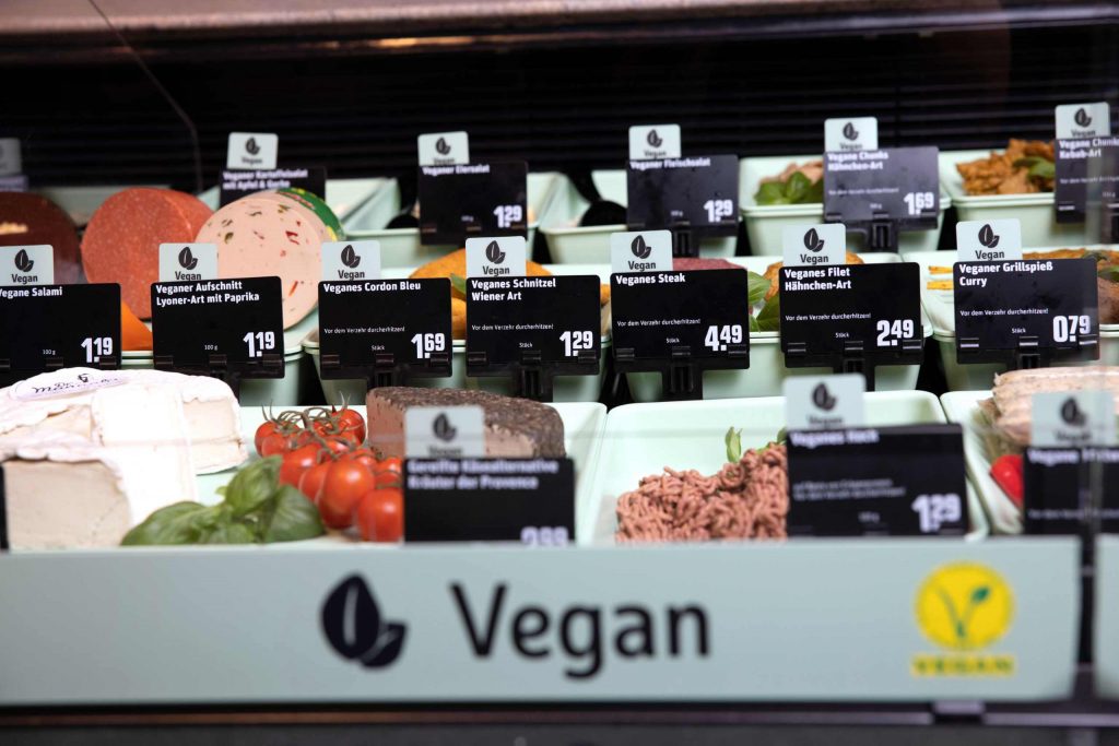 Auswahl veganer Speisen an der Bedientheke im REWE Markt