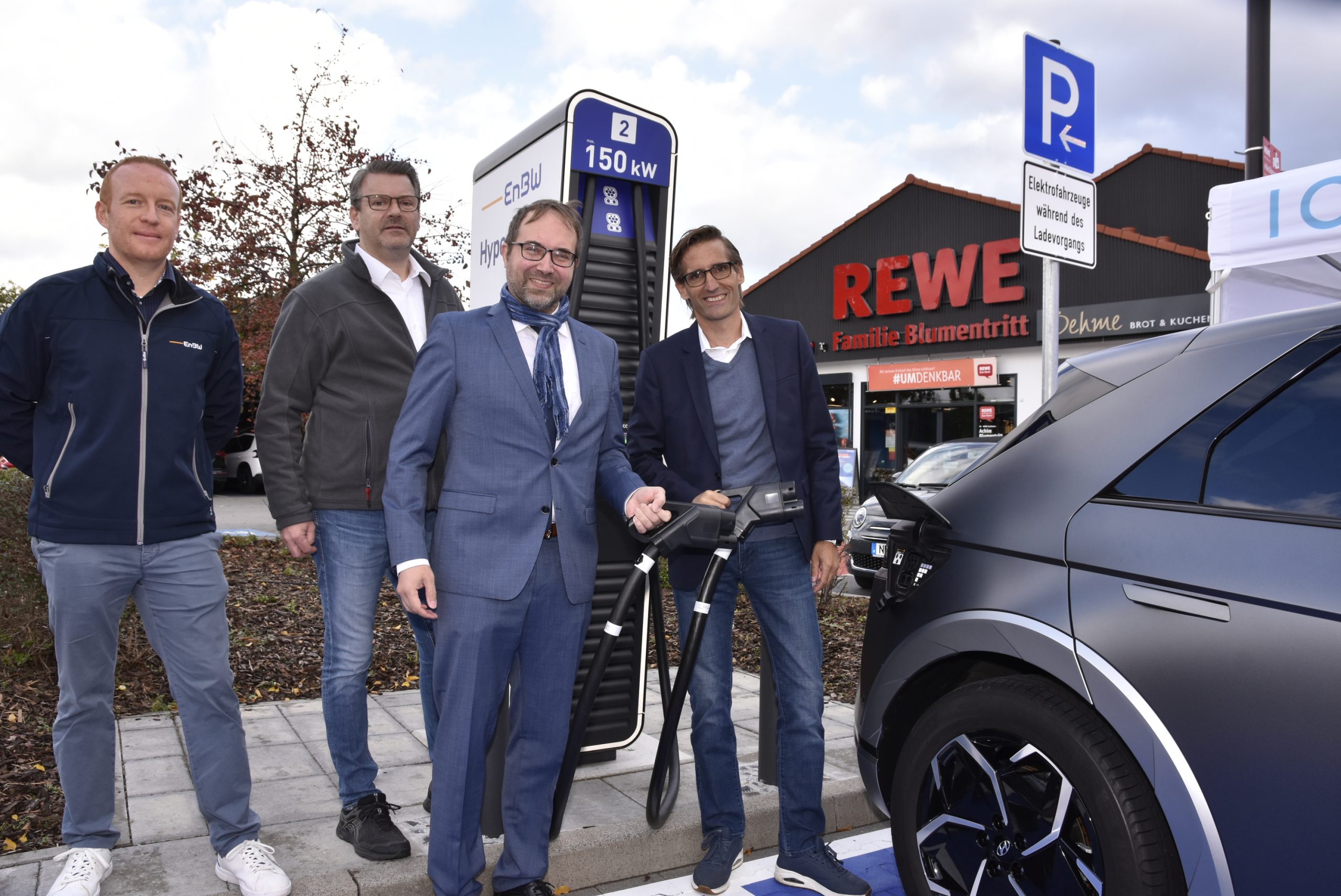Denis Horn, Marktleiter Achim Blumentritt, Telerik Schischmanow und Timo Sillober tanken Strom an der neuen Ladestation.