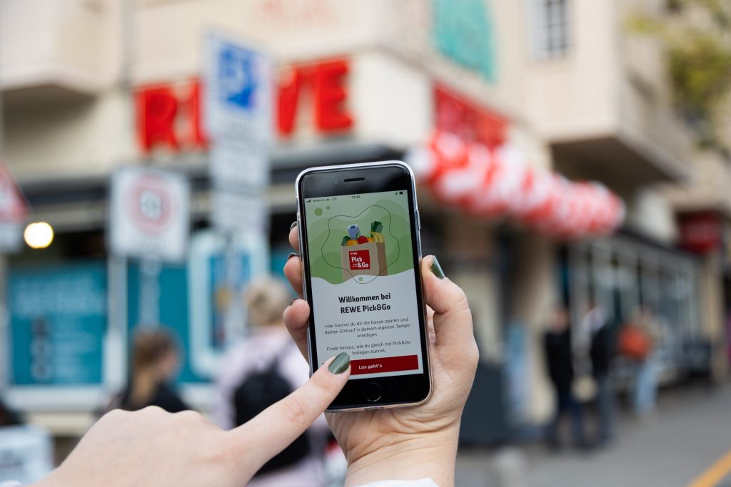 Hand mit Smartphone die sich in der Pick and Go App im REWE Markt registriert.