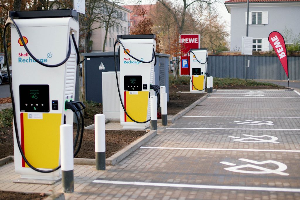 Ein Foto von einem REWE Parkplatz, auf dem drei Shell Ladesäulen stehen