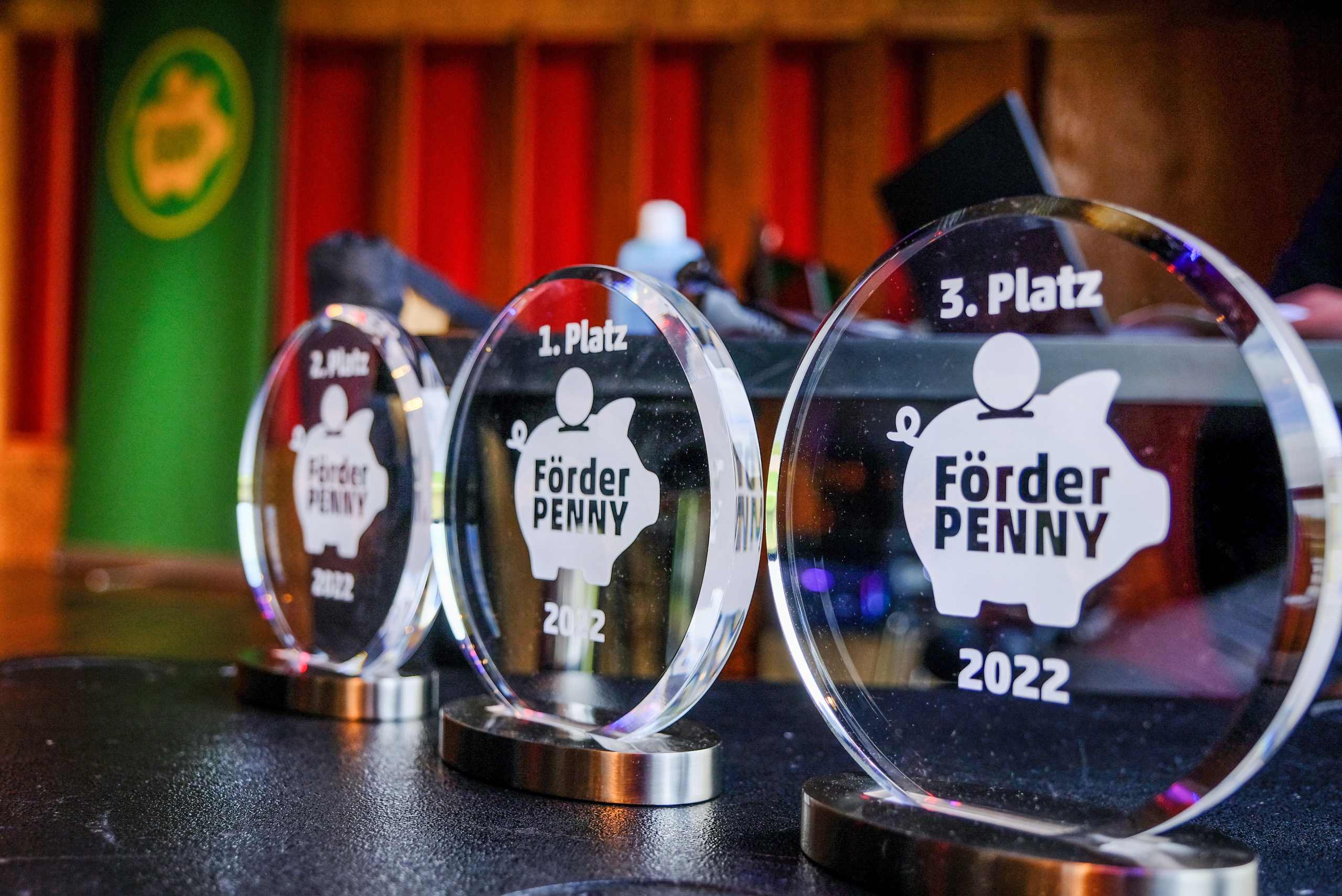 Drei gläserne Förderpenny Awards mit den verschieden Plätzen.