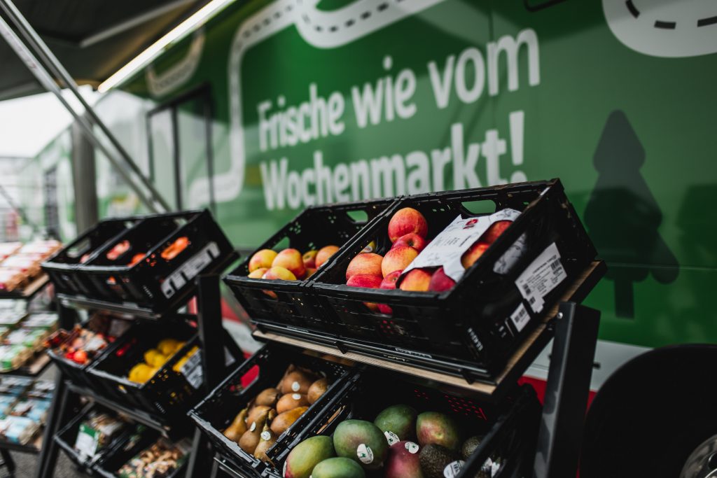 Kisten mit frischem Obst vor dem REWE-EInkaufsbus.