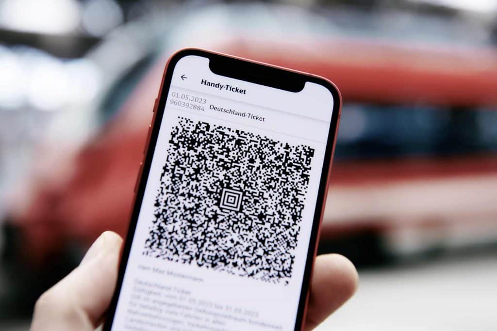 Hand mit Handydisplay auf dem der QR Code für das Deutschland-Ticket sichtbar ist