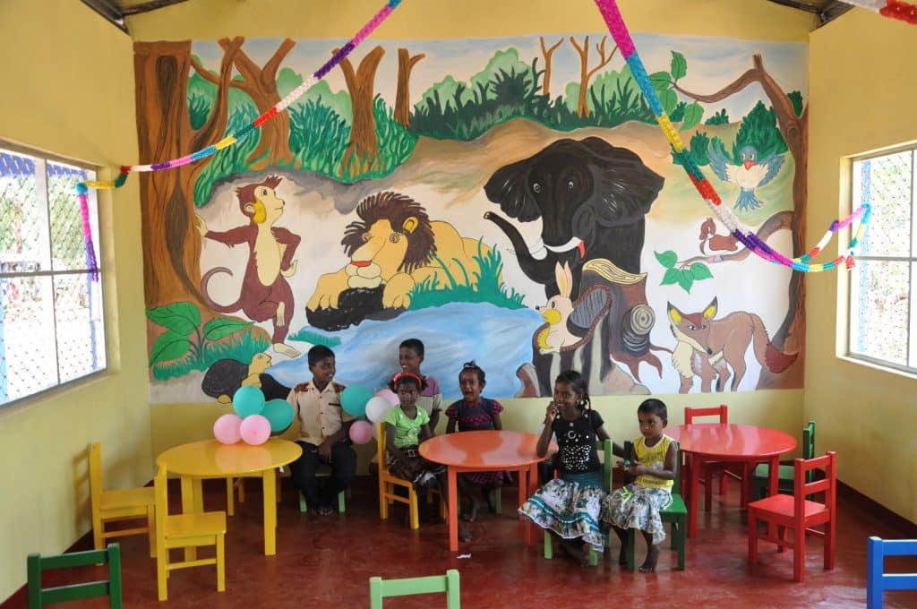 Bild von Kindern in einer Schule vor einer mit Zoo Motiven bemalten Wand.
