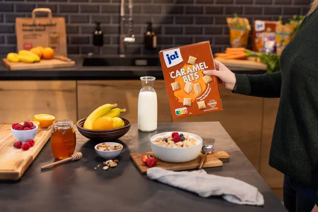 Küchenszene mit Obst und Müsli. Im Bild die Verpackung der Caramel Bites von ja! mit der Choviva Schokoladen Alternative