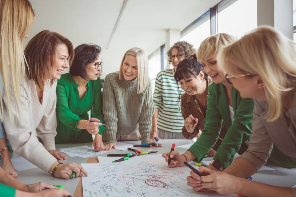 Frauen die in einem Kreis um einen Tisch stehen