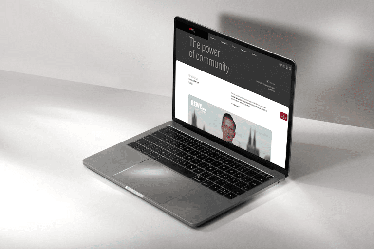 Open laptop showing the 2023 REWE GROUP Annual Report website on the screen