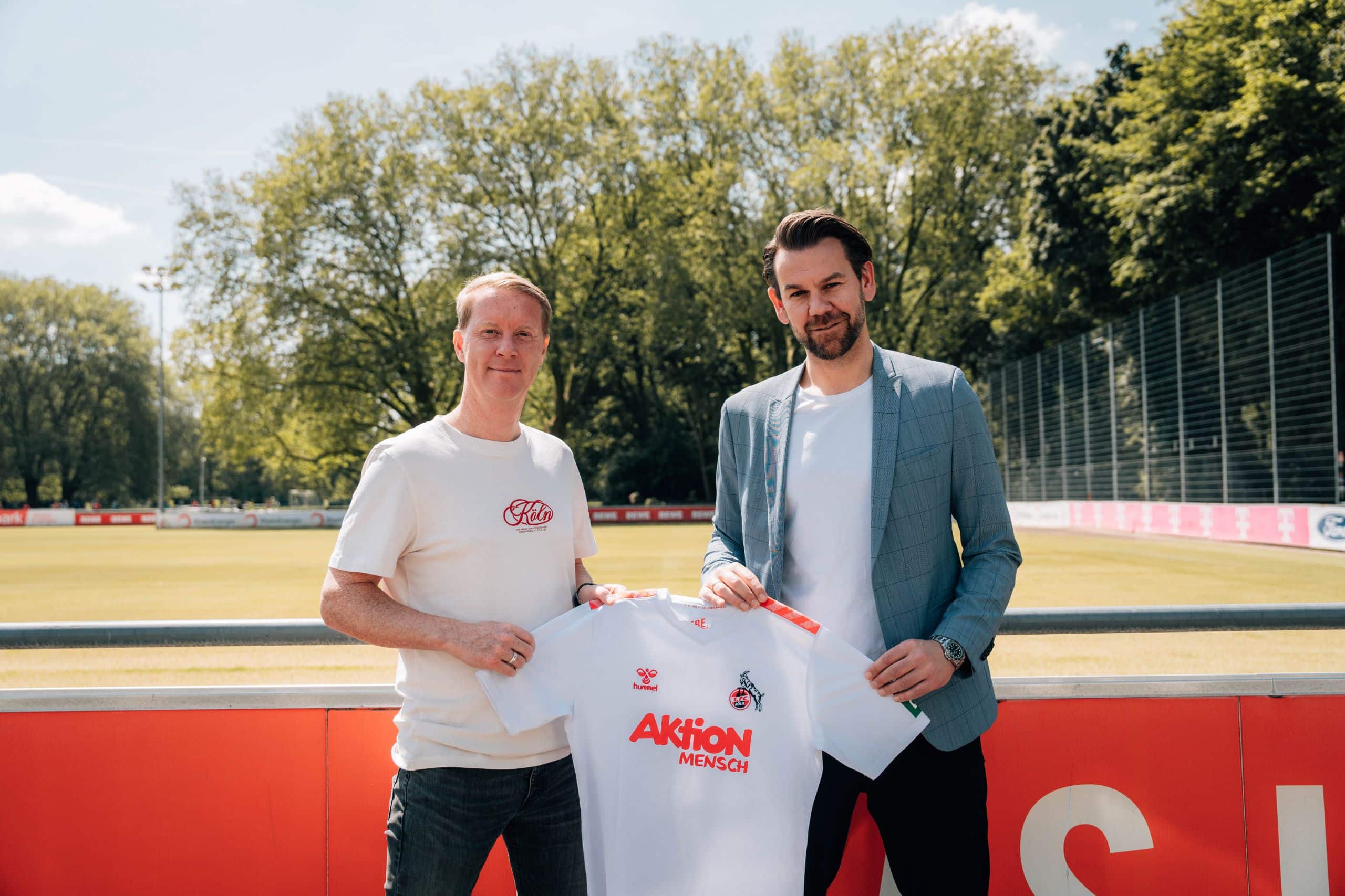 Im Bild ist links Trainer Timo Schultz zu sehen, rechts Thomas Kessler, Leiter der Lizenzspielerabteilung vom ersten FC Köln mit dem Aktion Mensch Trikot in der Hand.