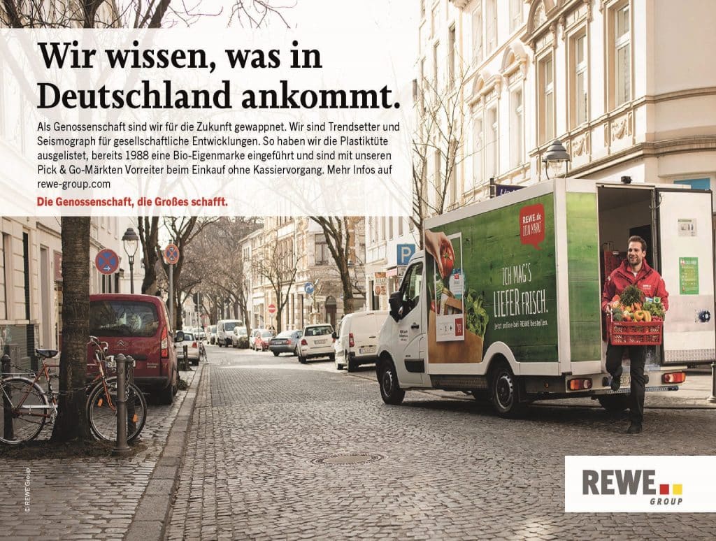 Ein Lieferwagen von REWE in einer Straße und ein Lieferservice-Mitarbeiter.