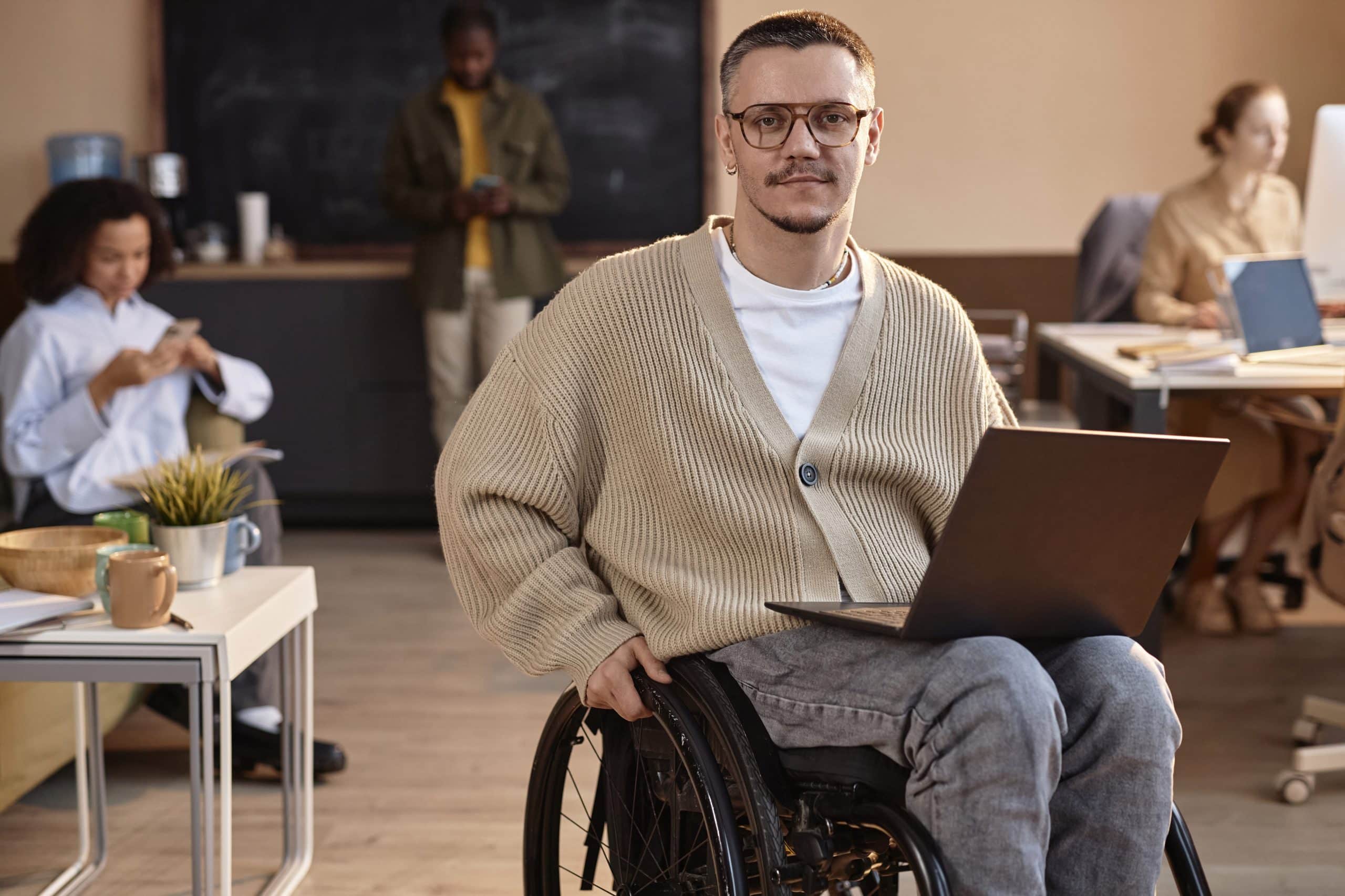 Geschäftsmann im Rollstuhl mit Laptop im Büro.