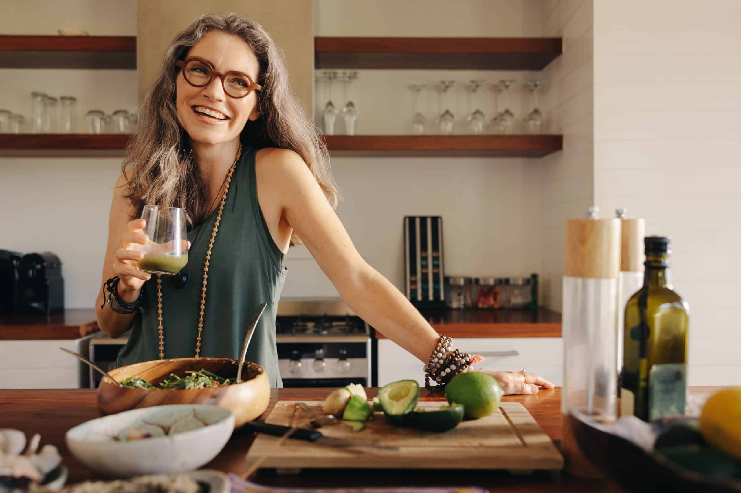 Frau in Küche mit grünem Saft und Salat