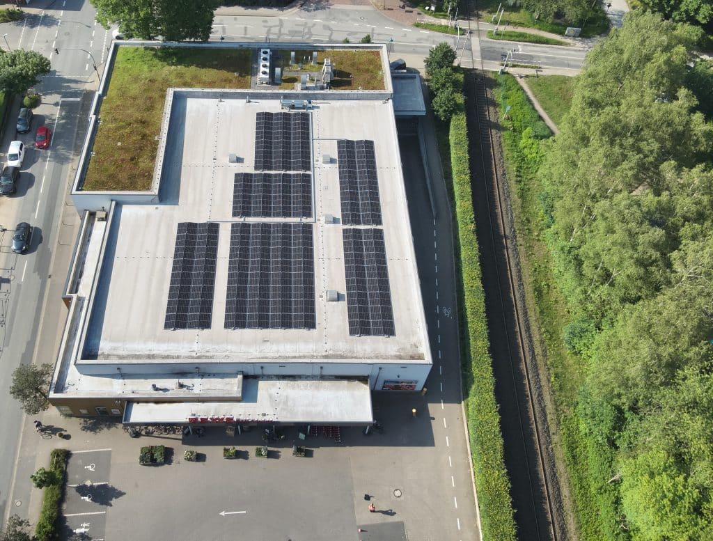 Luftaufnahme des REWE Buchholz mit Photovoltaik Anlagen auf dem Dach.