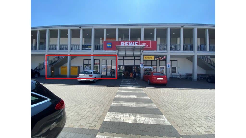 Außenansicht eines REWE Marktes mit Parkfläche.