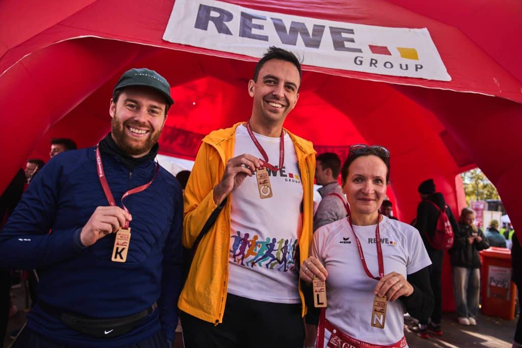Mitarbeitende der REWE Group mit Medaillen nach dem Köln Marathon