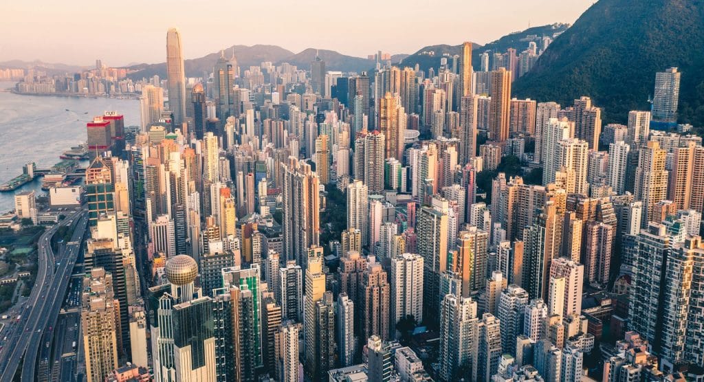 Luftaufnahme von Hong Kong mit vielen Hochhäusern am Wasser.