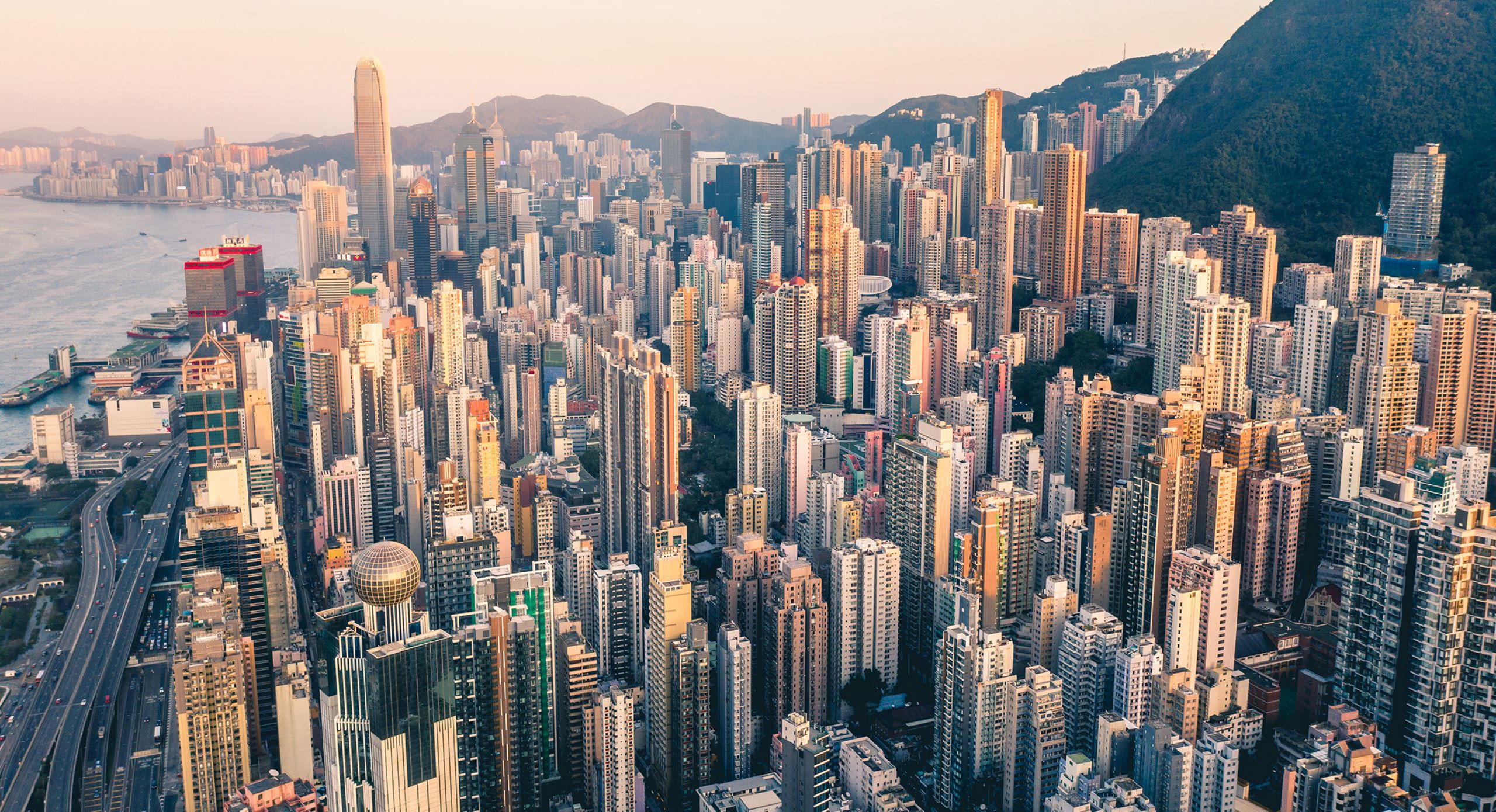 Luftaufnahme von Hong Kong mit vielen Hochhäusern am Wasser.