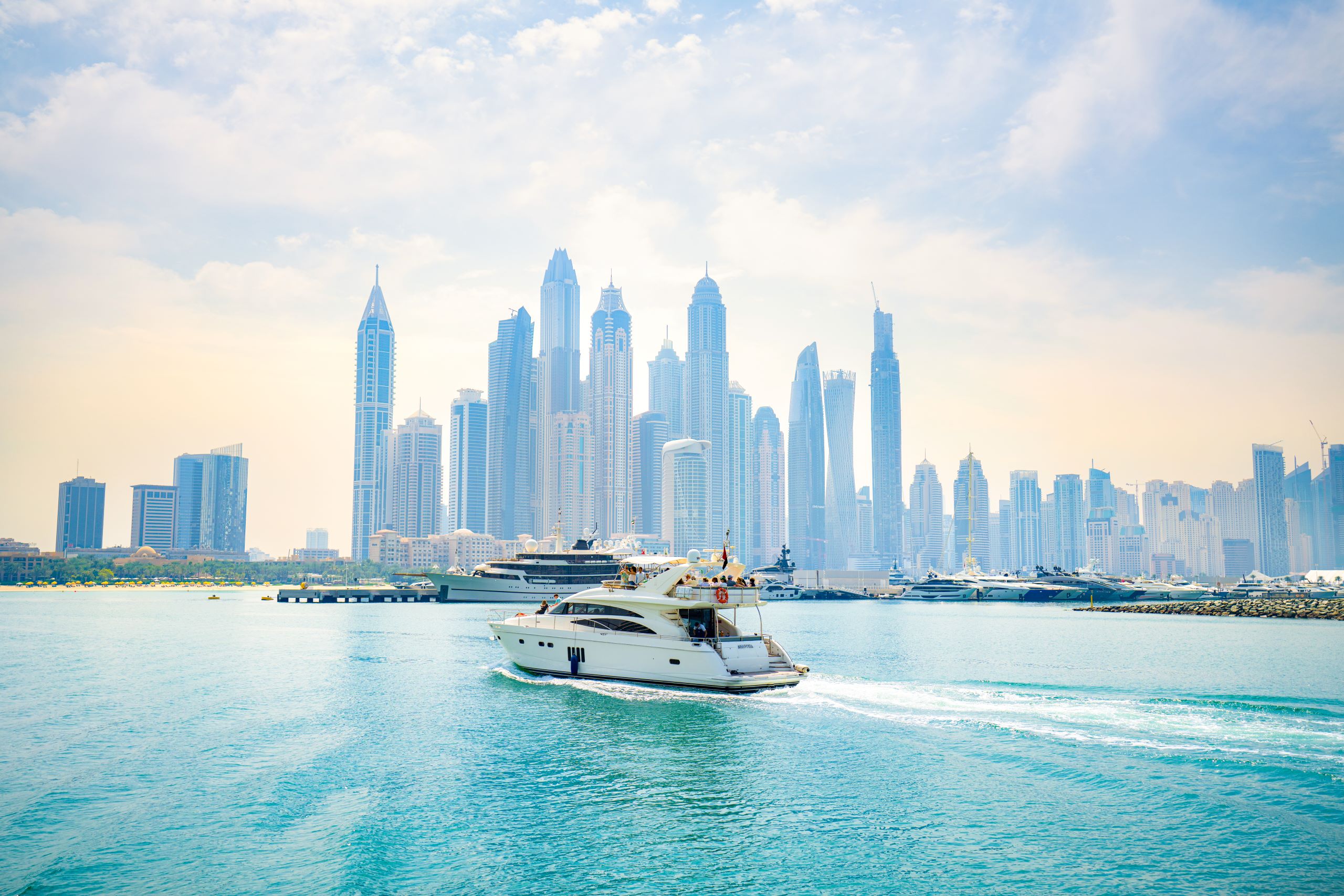 Skyline von Dubai mit Wasser und einem Boot im Vordergrund.