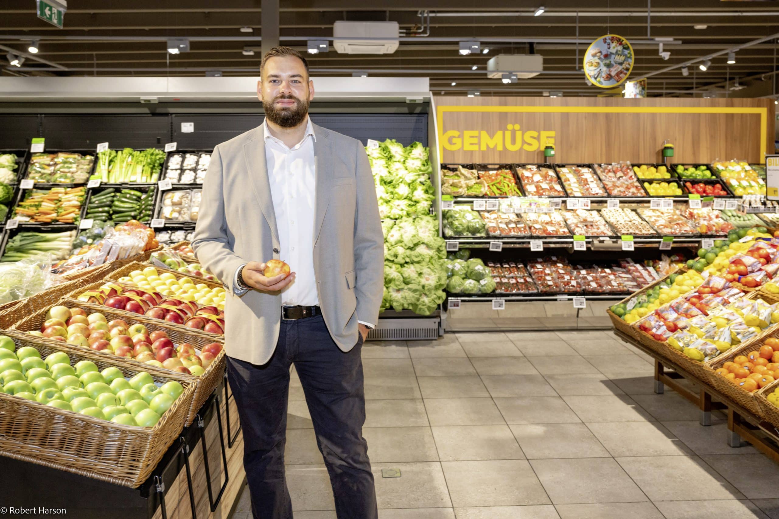 Porträt von Marko Miskovic. Er steht in einem BILLA Markt in der Gemüseabteilung.