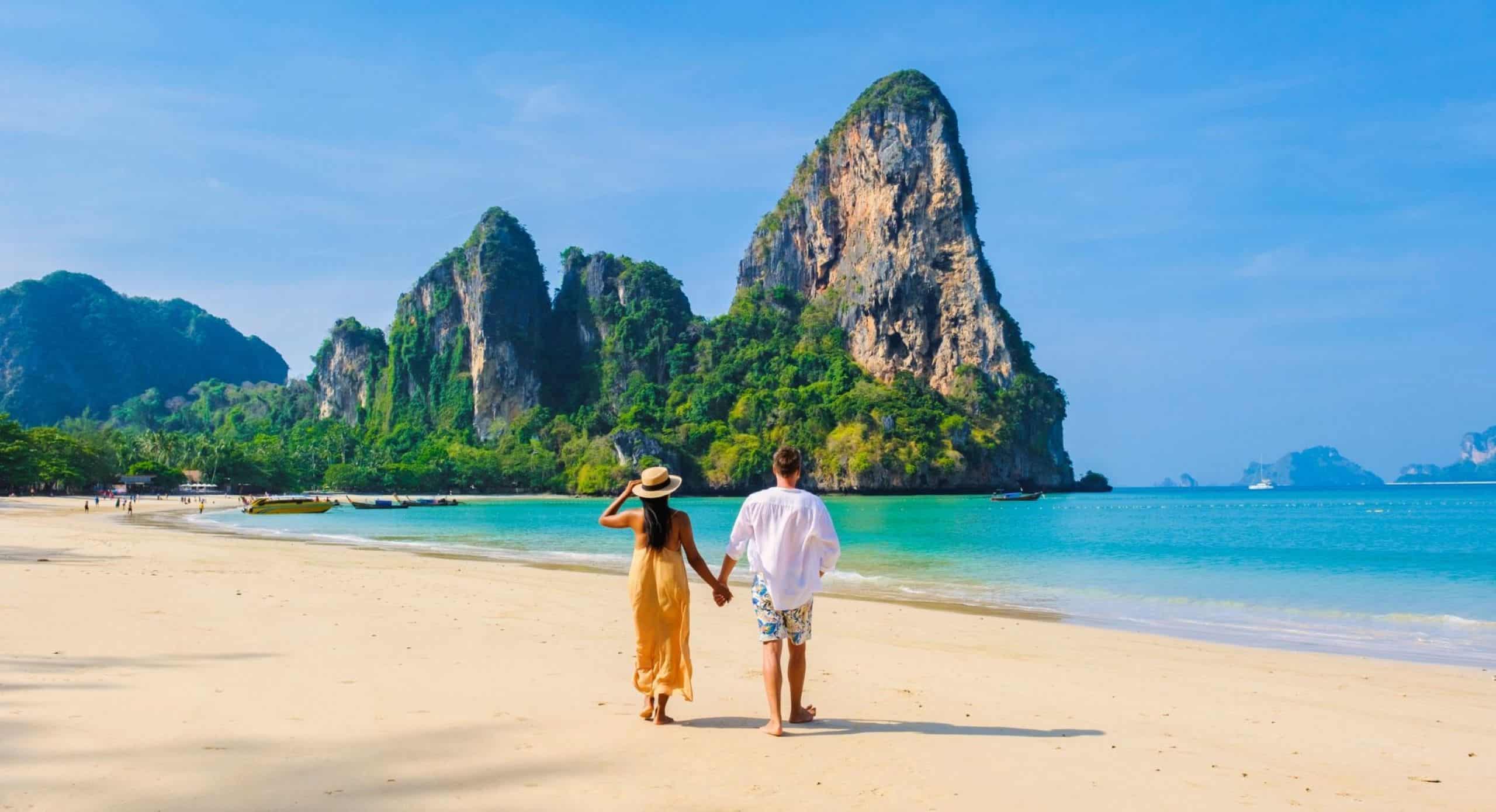 A couple walks hand in hand along the beach on the island of Krabi.
