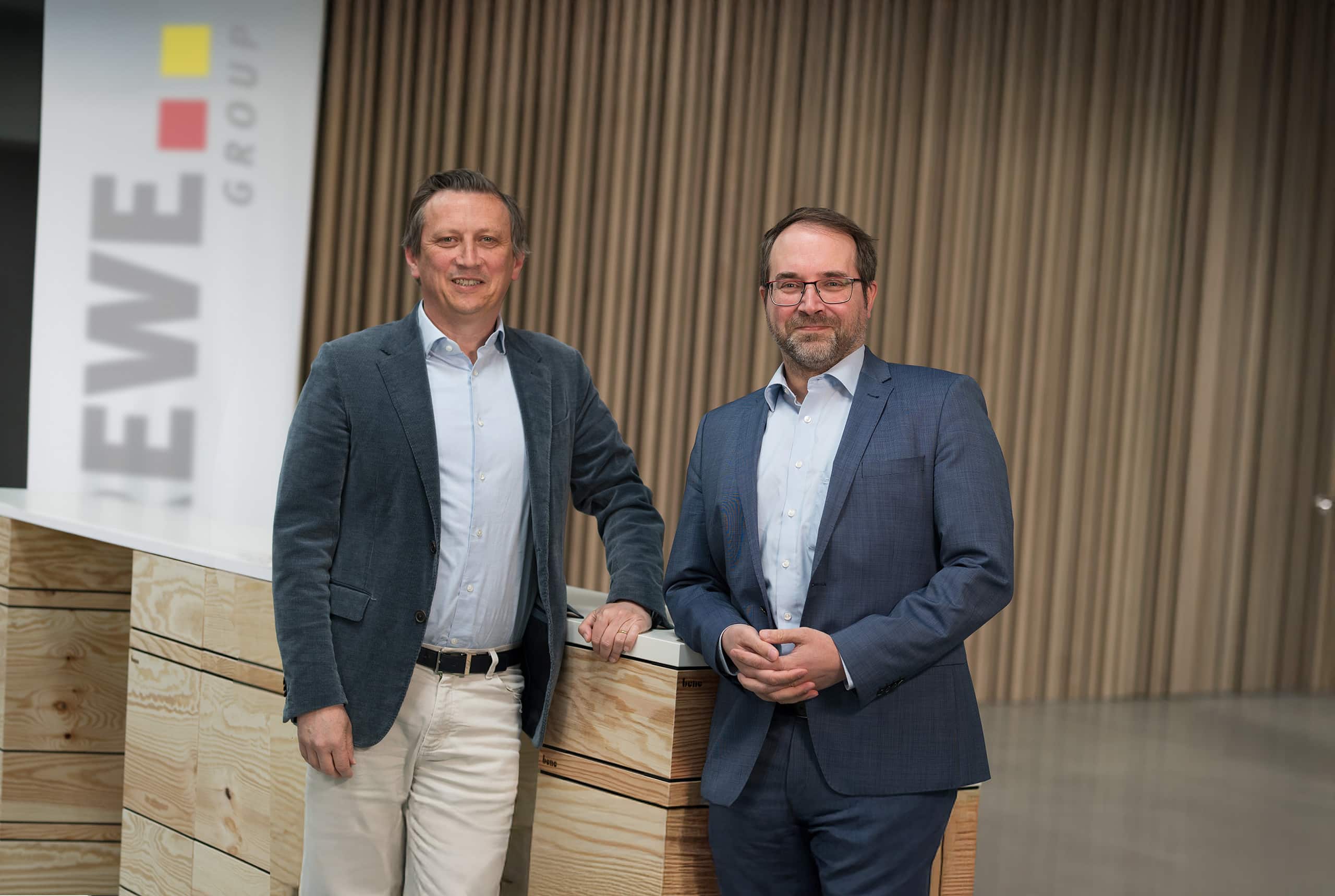 Lionel Souque und Telerik Schischmanow stehen nebeneinander and einem hölzernen Rednerpult und lächeln in die Kamera.