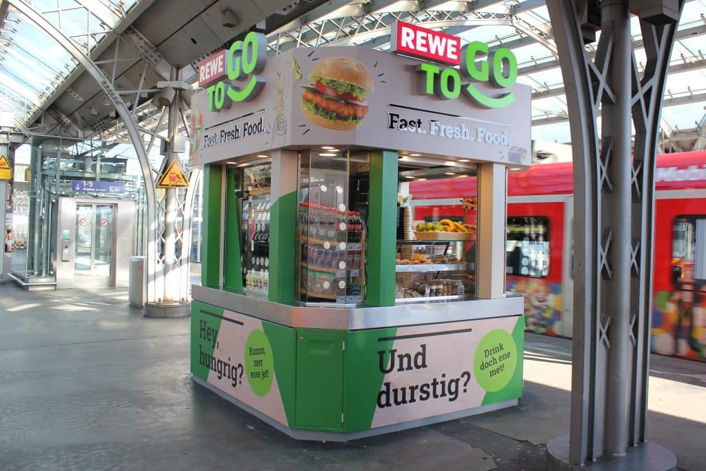 Außenansicht der REWE To Go Gleiskiosk am Kölner Hauptbahnhof.