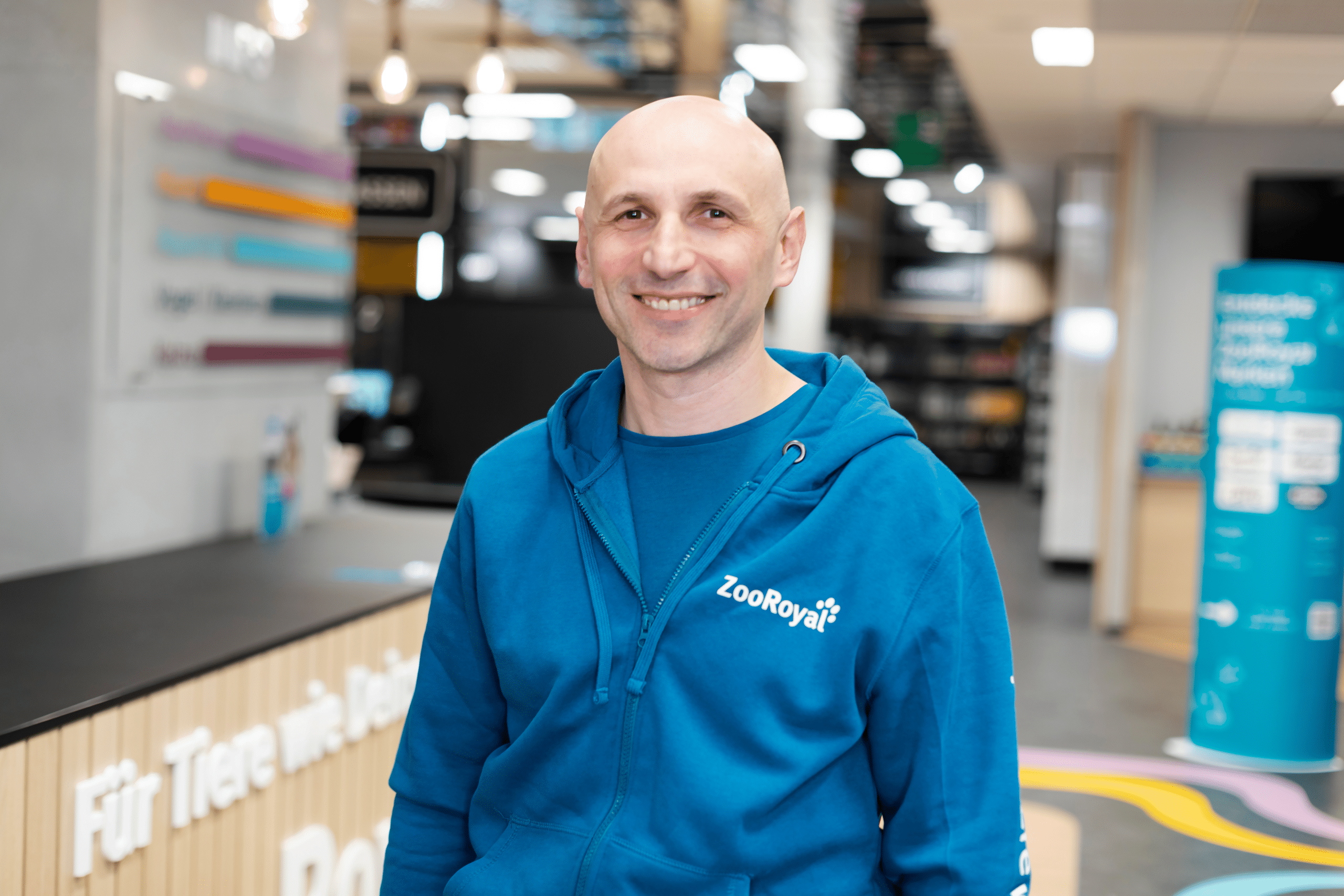 Porträt von Ivica Pobric. Er trägt eine blaue Jacke mit dem ZooRoyal Logo und lächelt in die Kamera.