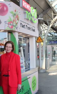 Jenny Ramme in front of the REWE To Go kiosk at Cologne Central Station