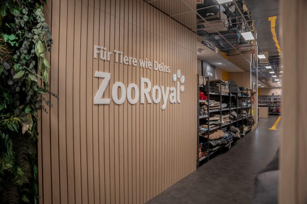Wand aus Holzpaneelen in einem ZooRoyal Markt mit dem ZooRoyal Logo und der Aufschrift 