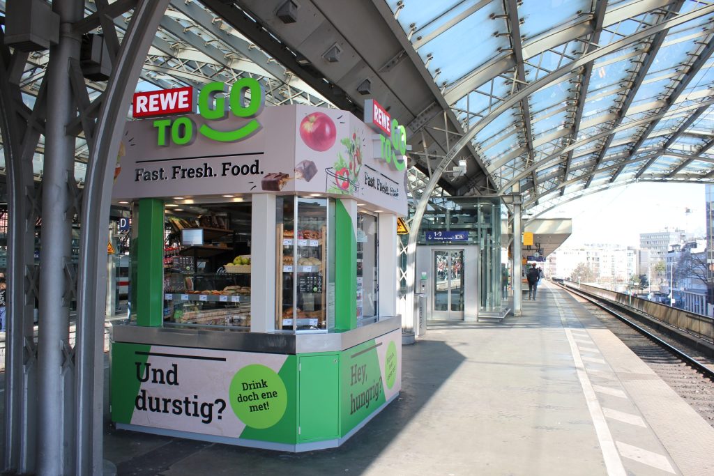 Exterior view of the REWE To Go platform kiosk at Cologne Central Station.