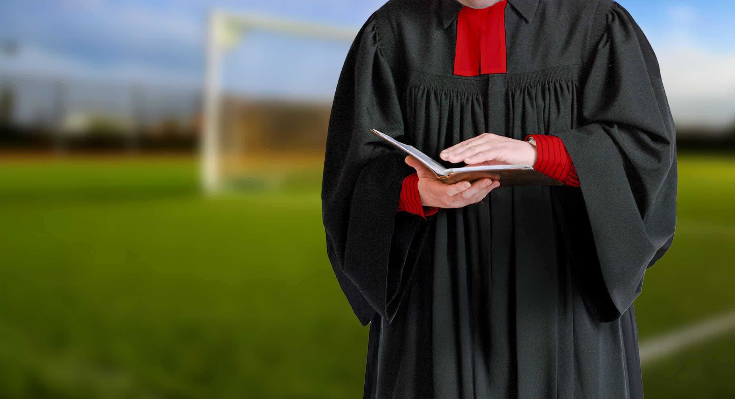 Ein Pastor mit einer Bibel in der Hand. Der Hintergrund ist verschwommen und zeigt eine grüne Wiese.