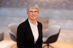 Porträt von Frauke Weber. Sie lacht in die Kamera, der Hintergrund ist grau.