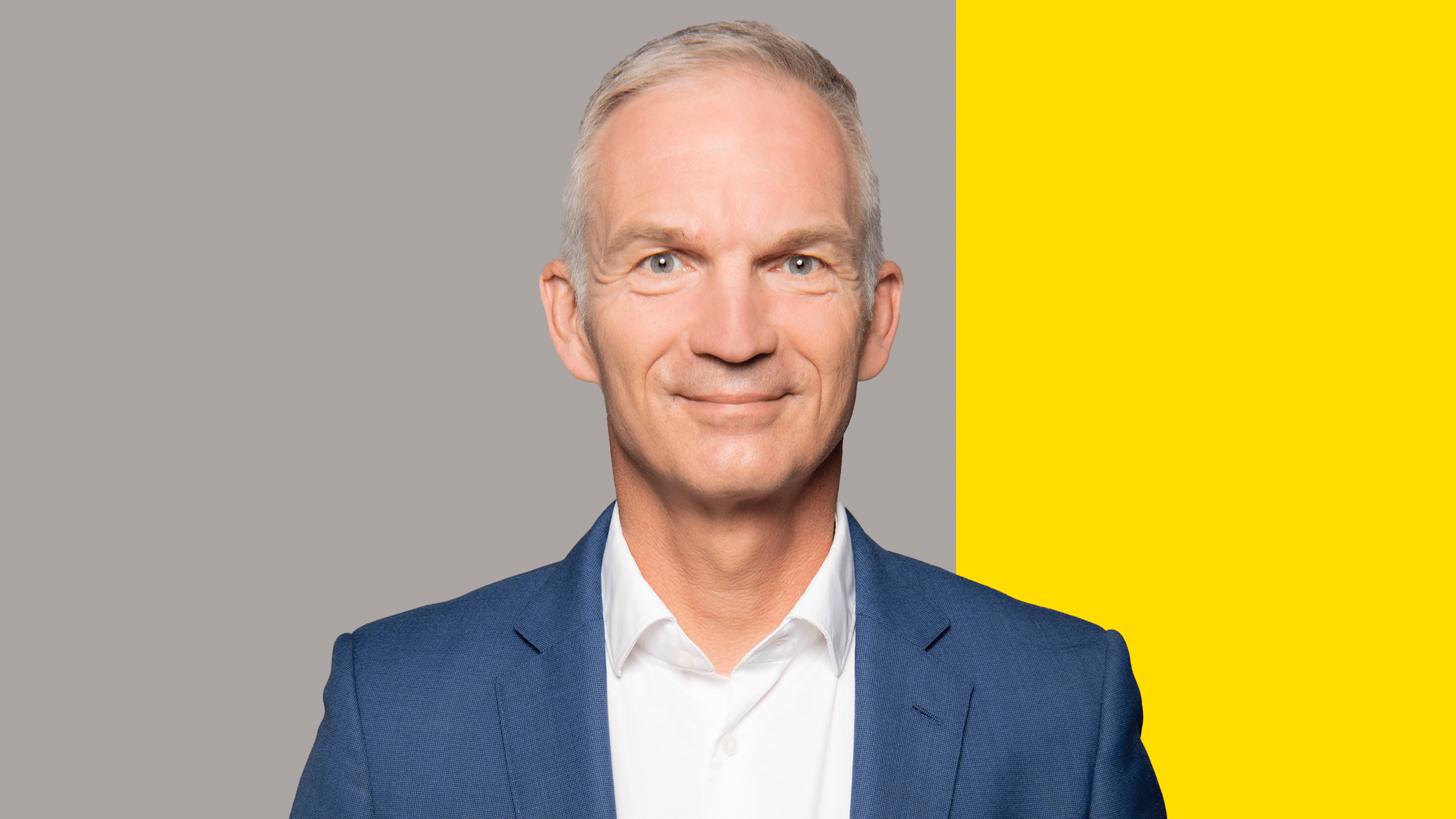Porträt von Thomas Nonn. Der Hintergrund ist grau mit einem gelben Balken.