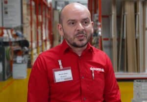 Porträt von Mentor Bilalli. Er trägt ein rotes Hemd mit dem toom Logo und steht im toom Markt.