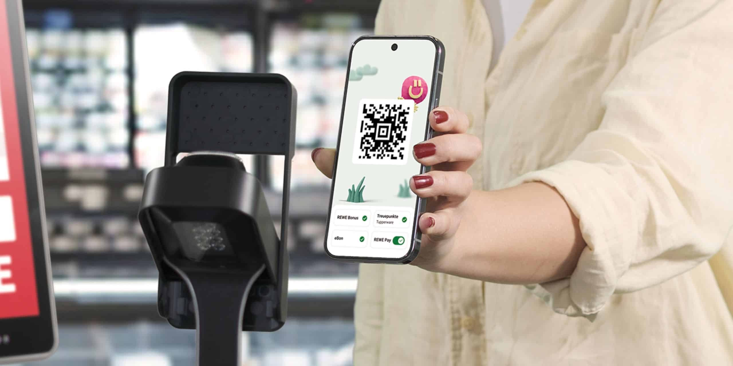 Eine Person hält ihr Handy mit geöffneter REWE App vor einen Scanner an der Kasse, um REWE Pay und das Bonusprogramm zu nutzen.
