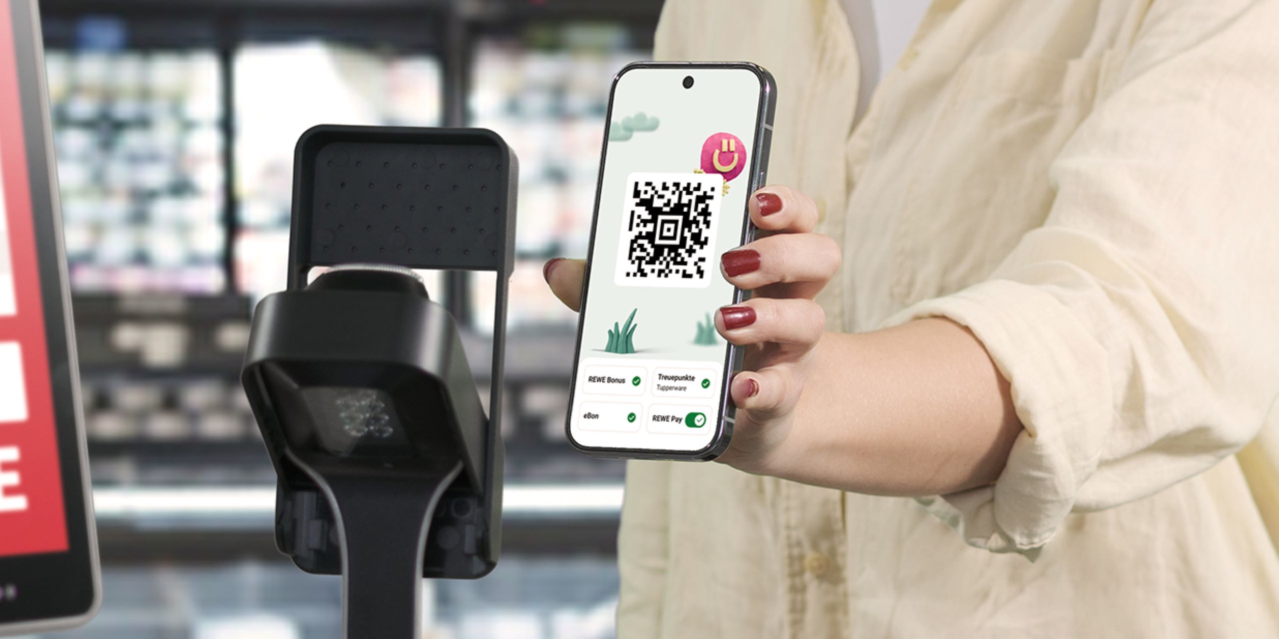 Eine Person hält ihr Handy mit geöffneter REWE App vor einen Scanner an der Kasse, um REWE Pay und das Bonusprogramm zu nutzen.