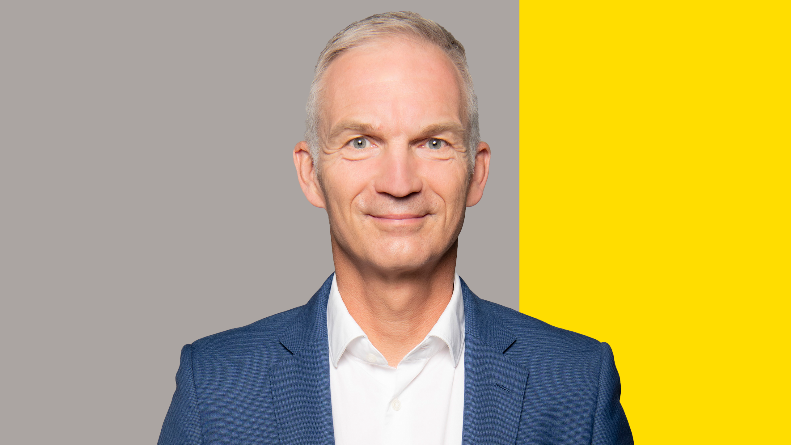 Portrait of Thomas Nonn. The background is gray with a yellow bar.
