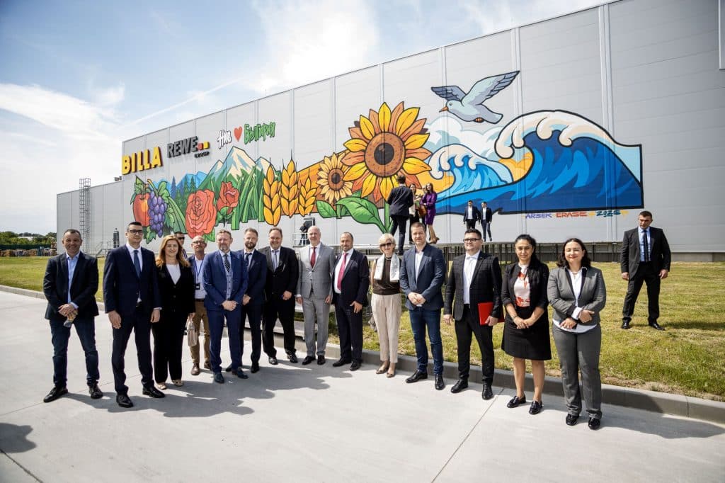 Eine Reihe von Menschen steht vor dem neuen Lager von BILLA CEE in Bulgarien. Ein beeindruckendes Graffiti, das von einem international beachteten bulgarischen Graffity-Künstler kreiert wurde, ziert das Lager und zeigt typische Symbole Bulgariens wie Früchte, Gemüse, Rosen und die Küste.