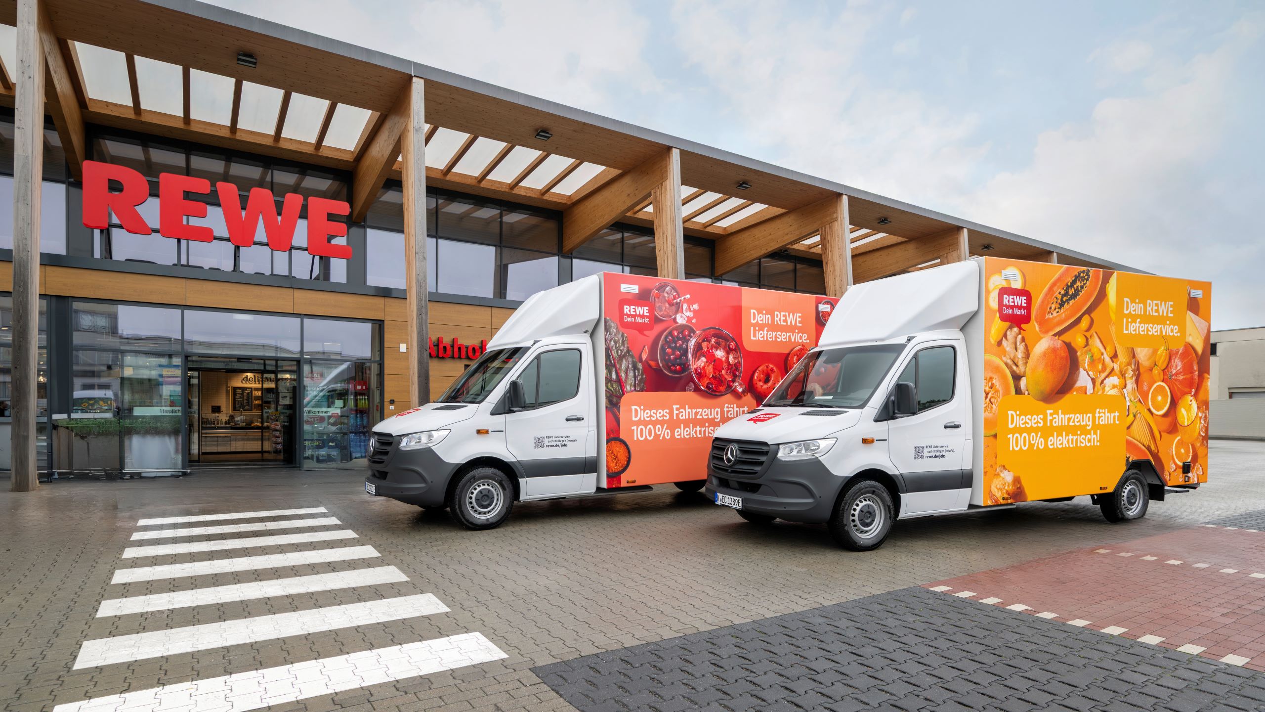 REWE delivery electric vehicles in front of REWE store.
