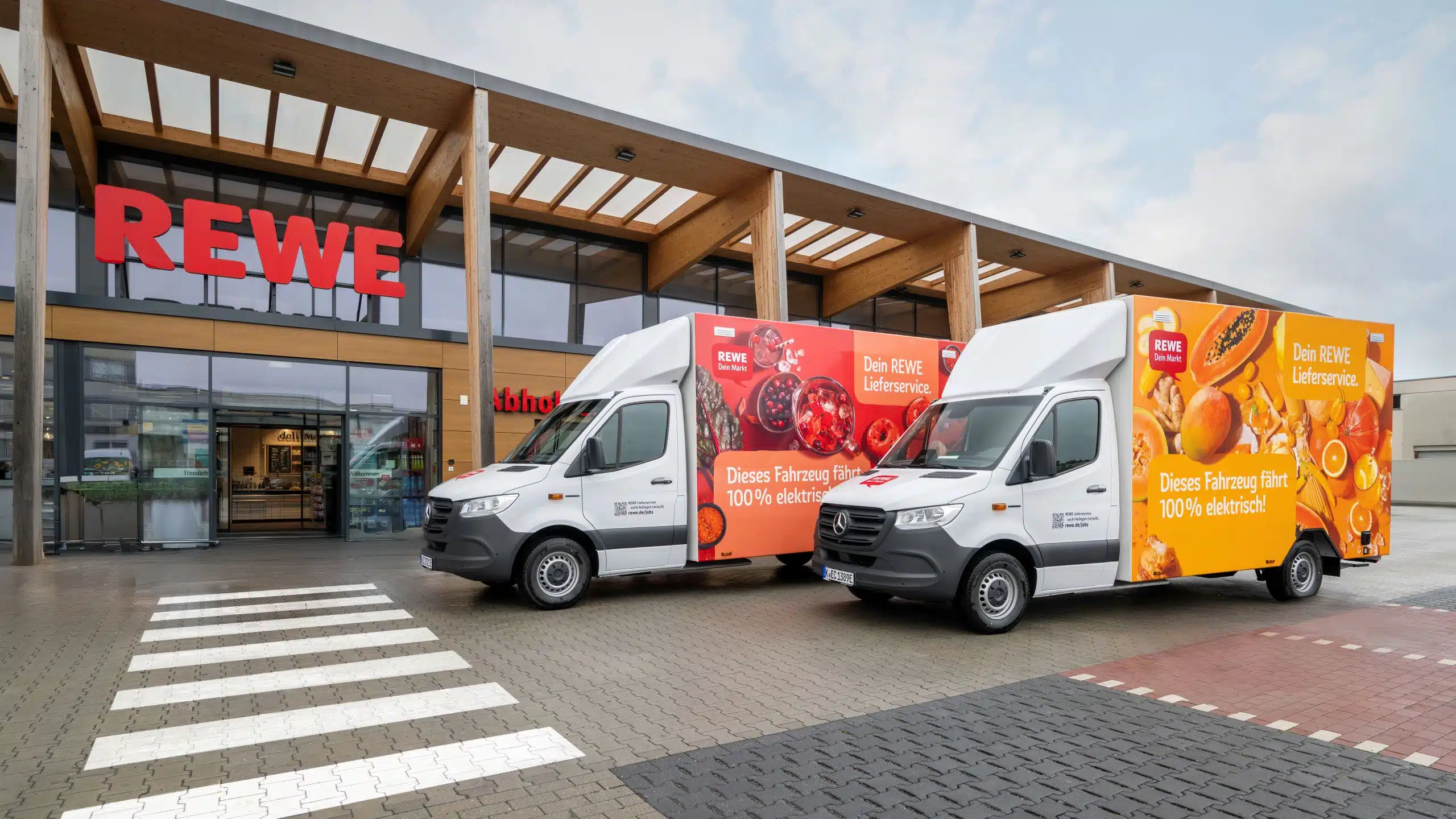 REWE Lieferelektrofahrzeuge vor REWE Markt.