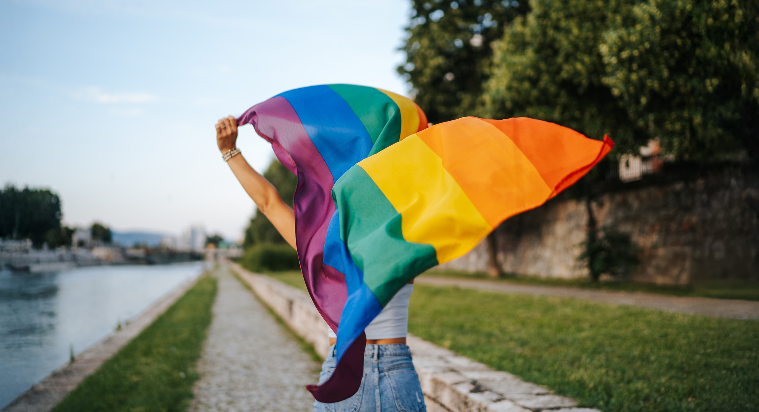 Eine Frau, von hinten gesehen, schwenkt die LGBTQ-Flagge.