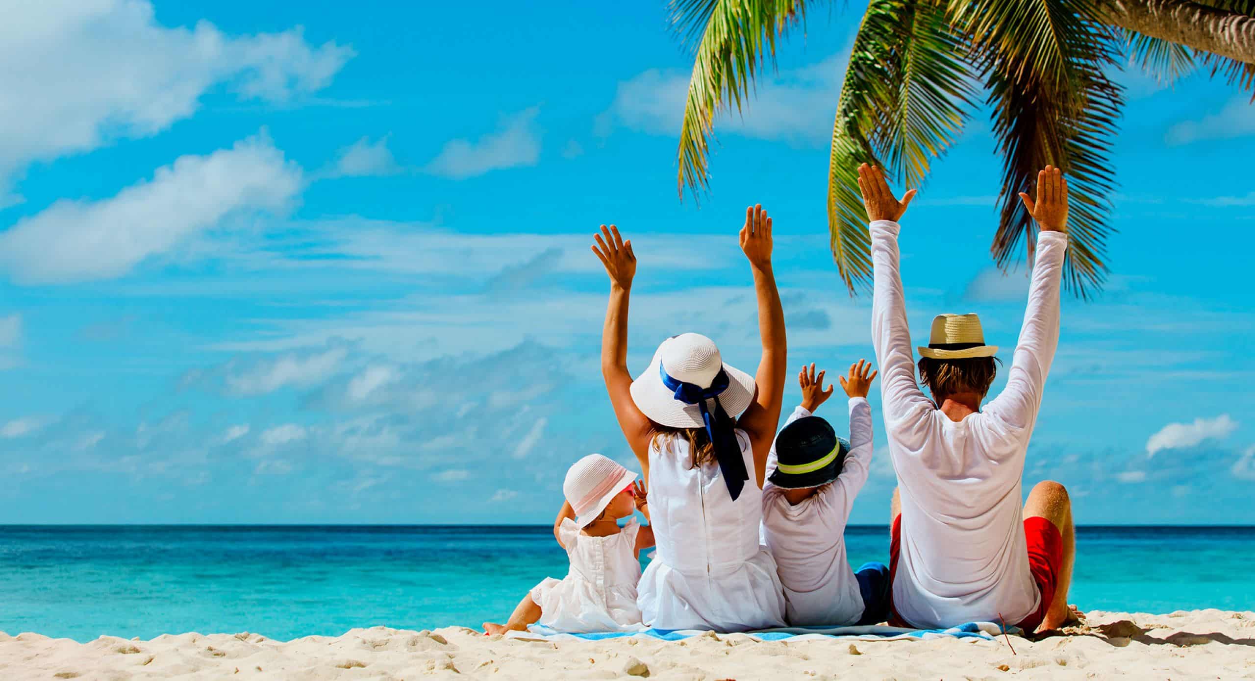 Eine Familie sitzt gemeinsam am Strand mit Blick auf das Meer.