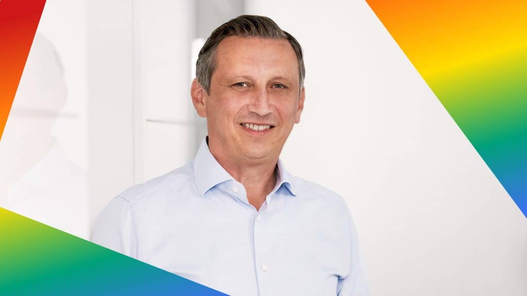 Porträt von Lionel Souque in einem Rahmen in den Farben der LGBTQIA+ Bewegung