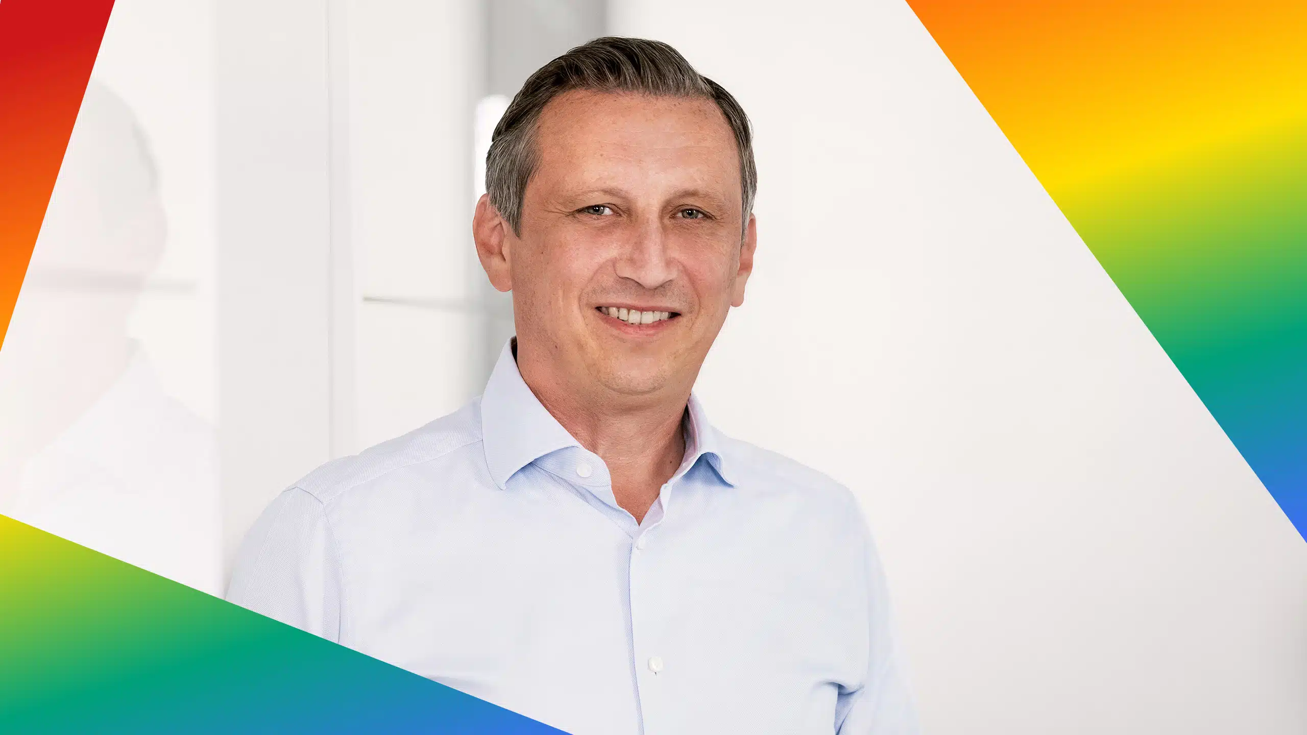 Porträt von Lionel Souque in einem Rahmen in den Farben der LGBTQIA+ Bewegung